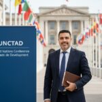 “Pepe Berzunza durante su visita a la sede de la UNCTAD en Ginebra, Suiza, frente a las banderas de Naciones Unidas, en una misión de cooperación internacional sobre políticas de emprendimiento.”